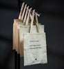 Set of beige tote bags with text on a dark background
