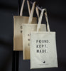 Three tote bags with text on a dark background