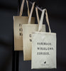 Three tote bags with text on a dark background